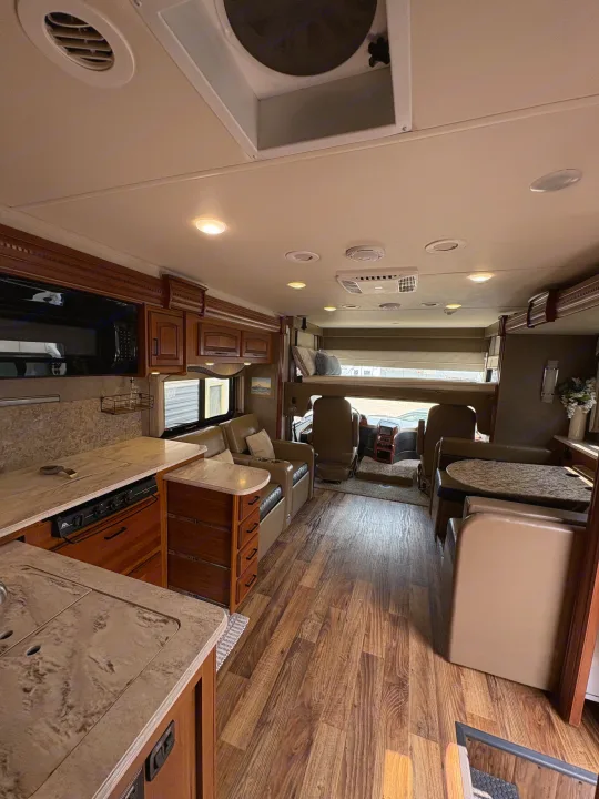 Spacious rv rental interior featuring a residential-style kitchen, dining booth, living area, and overhead bed.. Jayco Precept 2017