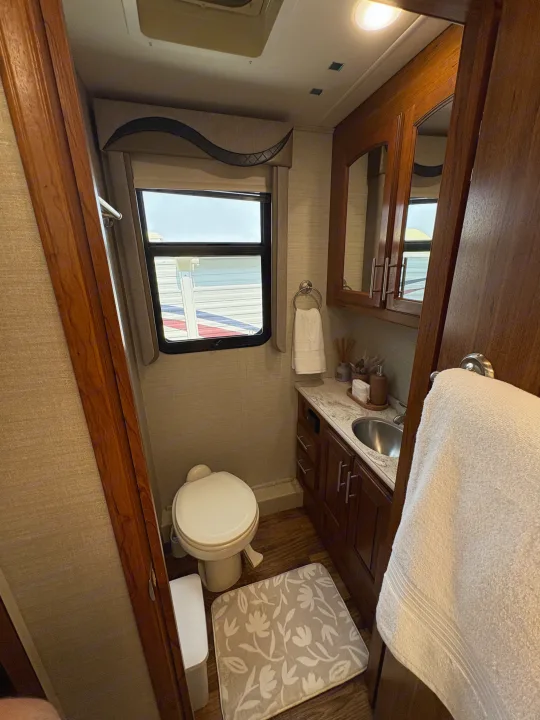 Compact RV rental bathroom features a toilet, sink vanity, mirror, and window, optimized for functional comfort.. Jayco Precept 2017