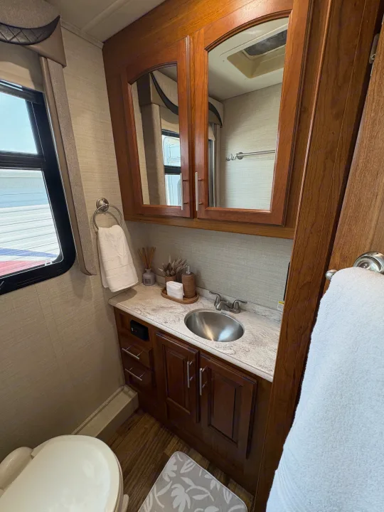 Compact RV rental bathroom with a vanity, sink, medicine cabinet, toilet, and window, providing essential amenities.. Jayco Precept 2017