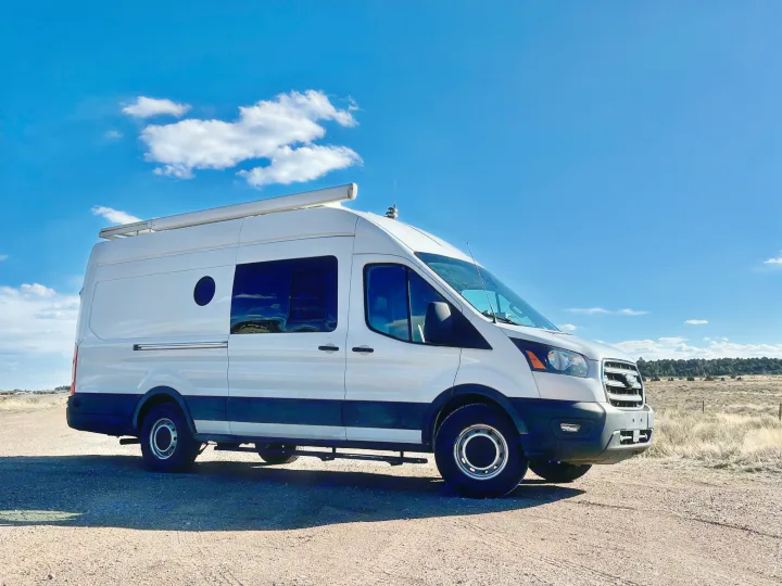 White custom camper van on a gravel road. Ideal RV rental for off-grid travel.. Ford Transit 350 High Roof EXT 2020