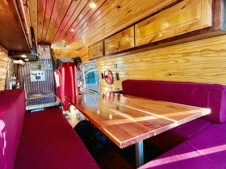 RV rental: Bright, warm wood interior with comfy purple benches & polished table, perfect for mobile living.. Ford Transit 350 High Roof EXT 2020