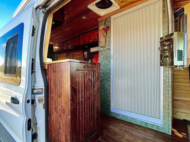 RV rental: Custom camper van interior with wood paneling, shower, and water heater, viewed from open side door.. Ford Transit 350 High Roof EXT 2020