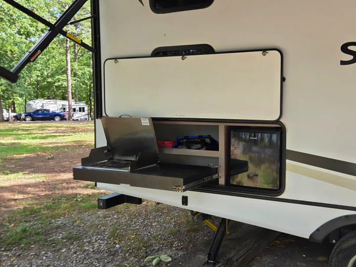 RV rental featuring an outdoor kitchen with a pull-out grill and Hotpoint mini-fridge, perfect for campsite cooking.. Crossroads RV Sunset Trail Super Lite 2022