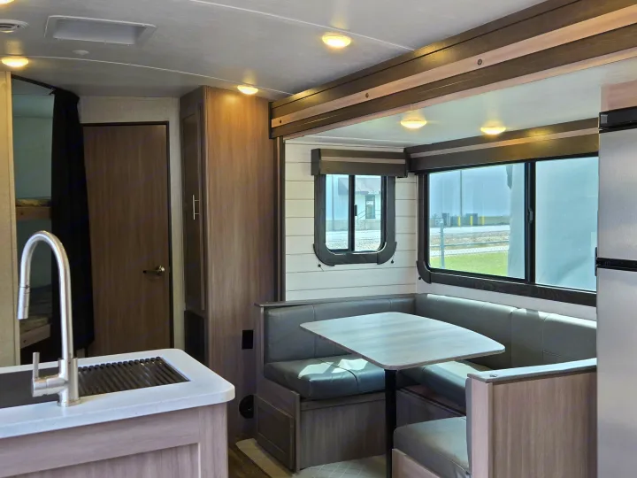 Modern RV rental interior: kitchen sink, dinette with booth seating, large windows, and bunk beds.. Crossroads RV Sunset Trail Super Lite 2022