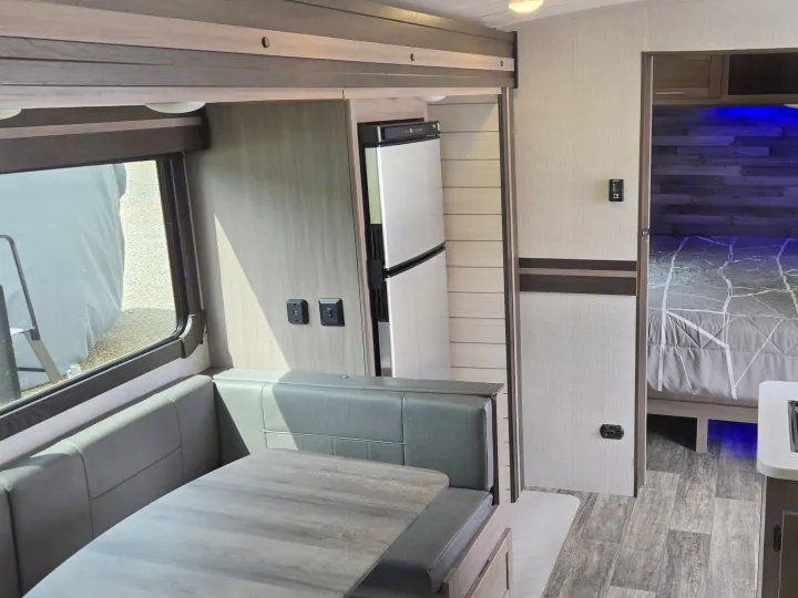 This rv rental interior features a dinette, full kitchen with sink, and a comfortable bedroom with blue accent lighting.. Crossroads RV Sunset Trail Super Lite 2022