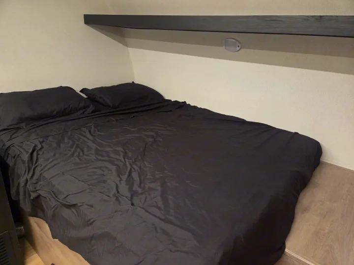 Cozy RV rental bedroom with black sheets, pillows, overhead shelf, and integrated light/USB ports.. Cruiser RV Embrace 2025