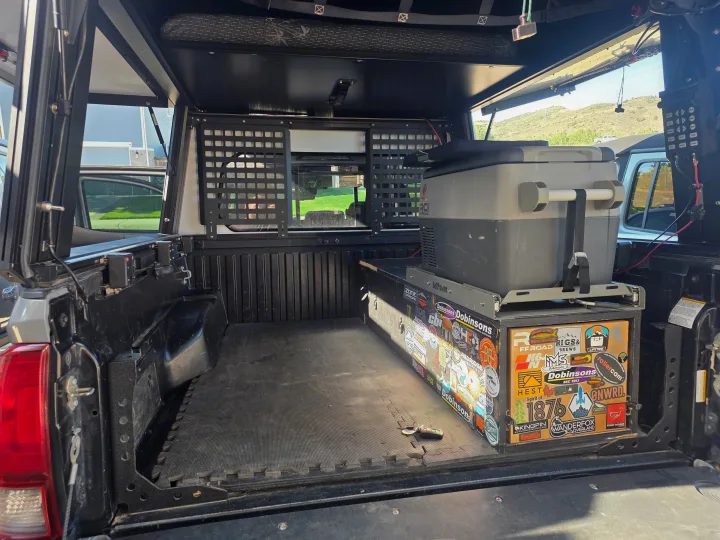Equipped truck bed camper for overlanding: fridge, storage, sleeping platform. Ready for adventure as an RV rental.. Toyota Tacoma 2018
