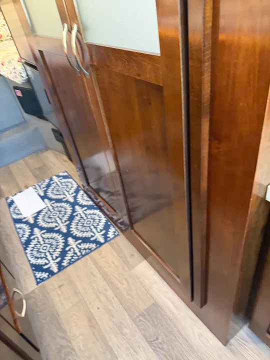 RV rental interior featuring dark wood cabinets with handles, light wood-look flooring, and a blue patterned rug.. Coachmen Galleria 2020