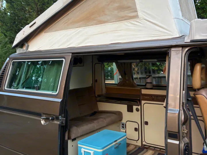 Open side of a vintage VW Westfalia camper van with extended pop-top, showing its cozy interior. Ideal rv rental for camping.. Volkswagen Westfalia 1986