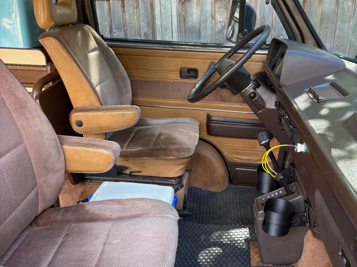 Get ready for your journey in this cozy rv rental! Features comfortable brown/beige seats, steering wheel, and handy cup holders.. Volkswagen Westfalia 1986