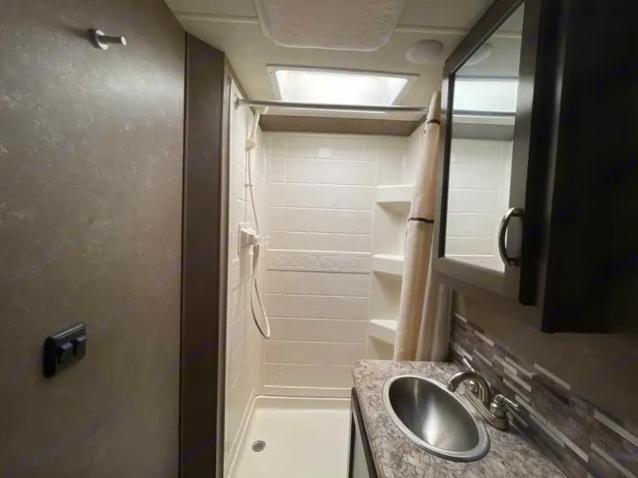 Compact RV rental bathroom featuring a bright shower, practical sink, and mirrored cabinet. Perfect for travel.. Thor Freedom Elite 2020