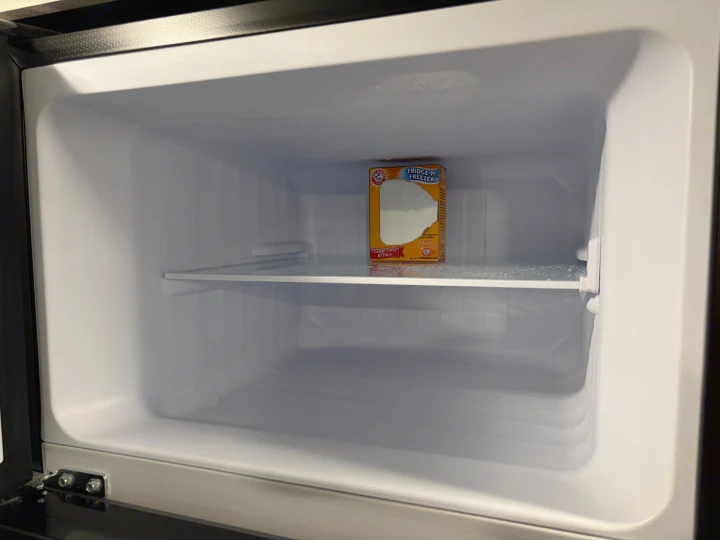 Clean, empty compact fridge/freezer in an RV rental, with an open box of baking soda for odor control.. Jayco Jay Flight SLX 2024