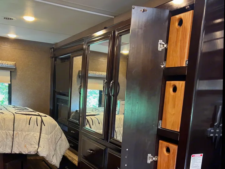 RV rental: Modern interior featuring a bed, dark wood cabinets, and clever kitchen storage with vertical cutting boards.. Thor Quantum 2017