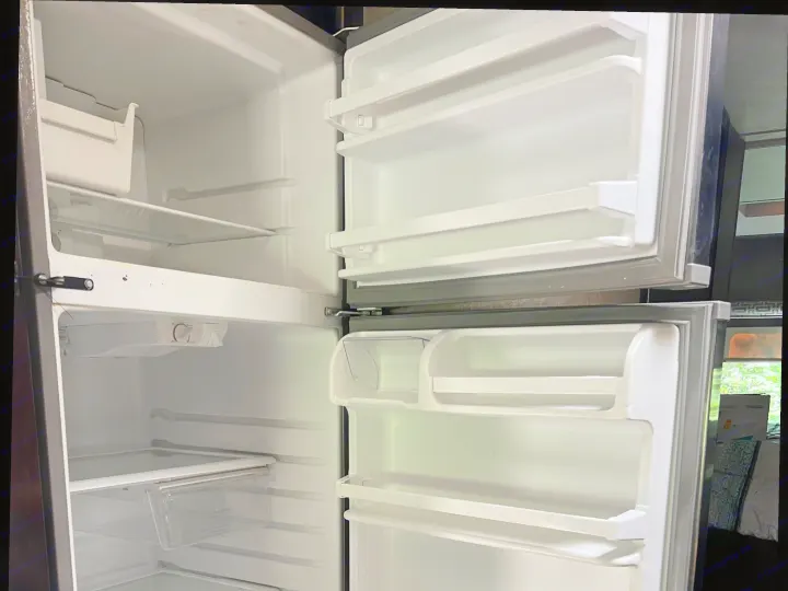 Inside a clean, empty RV rental refrigerator with open doors, revealing shelves in freezer and fridge compartments, ready for use.. Thor Quantum 2017