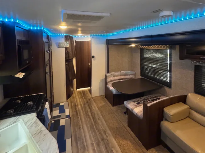 Bright RV rental interior: kitchen, dinette, and living area. Blue LED lighting creates a cozy, inviting atmosphere.. Jayco Jay Flight SLX 2020