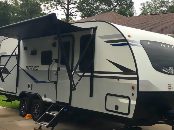 Experience outdoor leisure! This modern white and gray Sonic travel trailer, ideal for RV rental, features an extended awning.. Sonic Sonic Trailer 2022