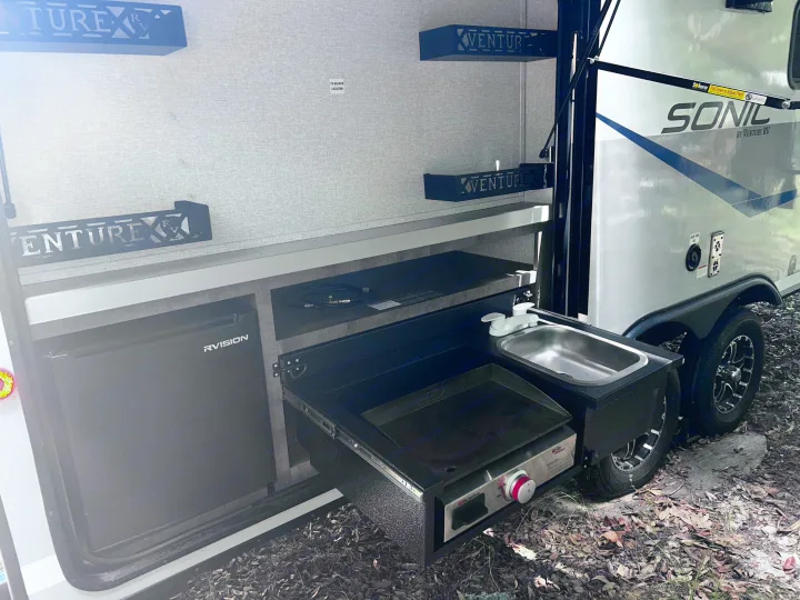This RV rental's outdoor kitchen features a sink, griddle, and fridge, perfect for camping and travel adventures.. Sonic Sonic Trailer 2022