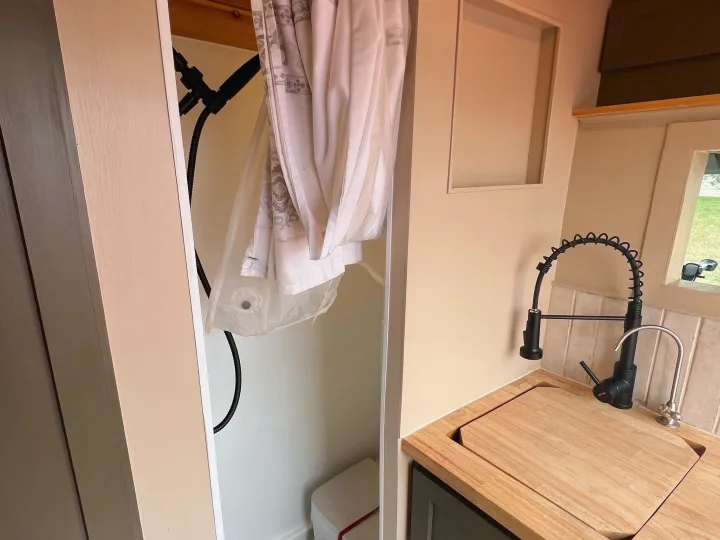 RV rental interior: compact shower with curtain, and kitchenette with sink, cutting board, and pull-down faucet.. Dodge Ram Promaster 2500 2020