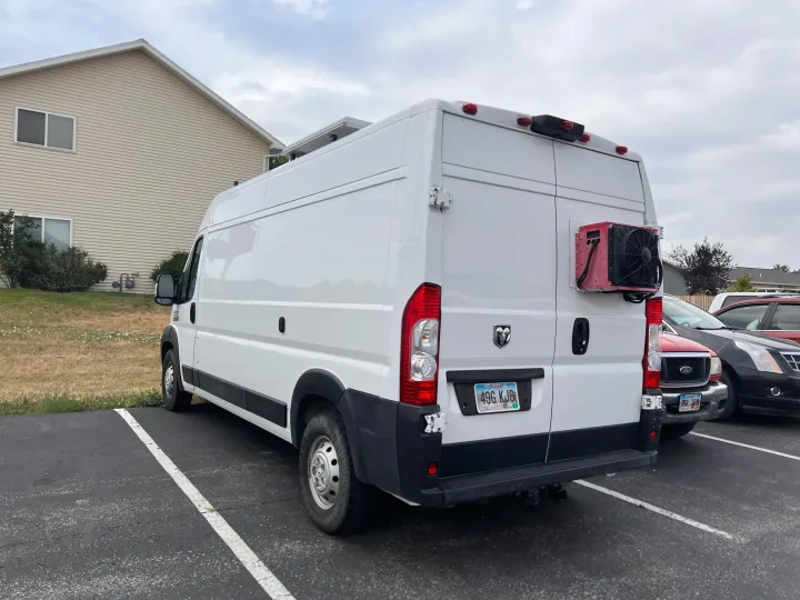 White Ram ProMaster rv rental conversion van with an external cooling unit, parked in a lot beside other vehicles.. Dodge Ram Promaster 2500 2020
