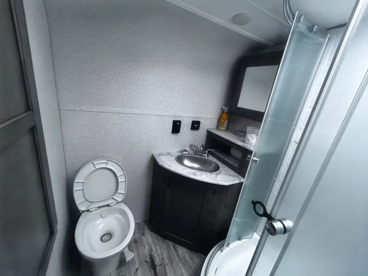 This RV rental bathroom features a toilet, sink, vanity with mirror, and a compact shower, ideal for travel.. Sonic Sonic Trailer 2022