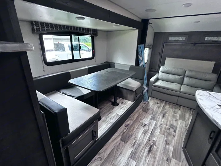 This rv rental features a cozy grey dinette, dark table, and matching sofa. Wood-look flooring completes the inviting camper interior.. Sonic Sonic Trailer 2022