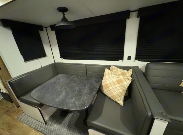 Modern RV rental dinette with black seating, marble-look table, and plaid pillows. Features blackout blinds.. Forest River Cherokee 2022