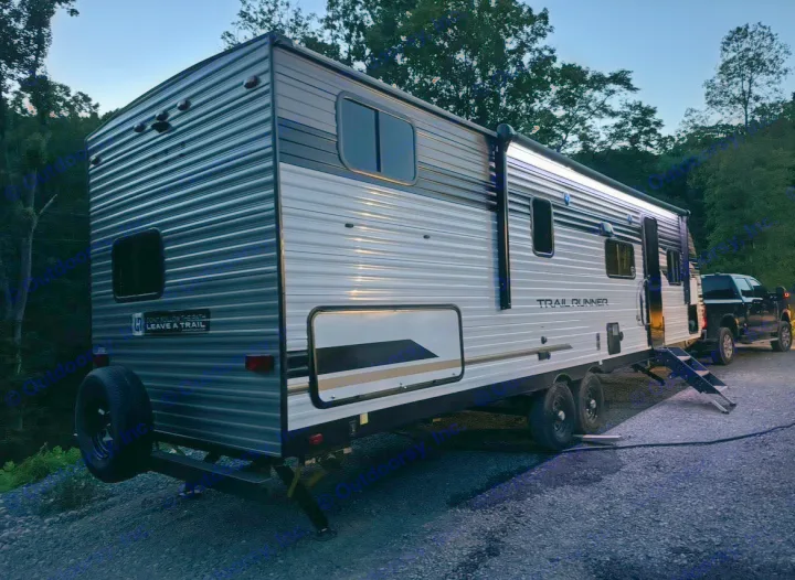 Night scene of a "Trail Runner" travel trailer RV rental, with illuminated awning, steps, and a truck parked nearby, ready for camping.. Forest River Cherokee 2022