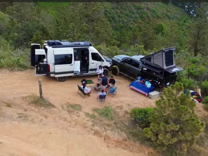 Group camping with an RV rental camper van and truck with a rooftop tent in a natural setting, enjoying outdoor adventure.. Winnebago Revel 2021
