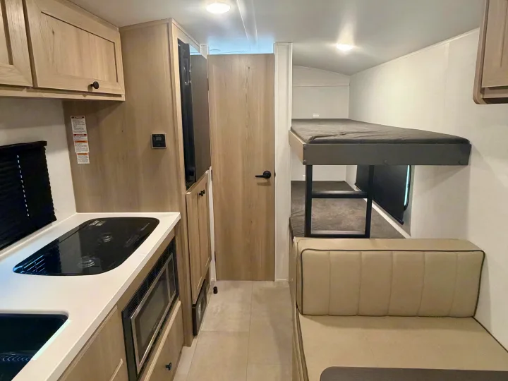 Inside this RV rental: a modern kitchen, comfortable dinette seating, and double bunk beds for travel comfort.. Forest River Rockwood Geo Pro 17LE 2026