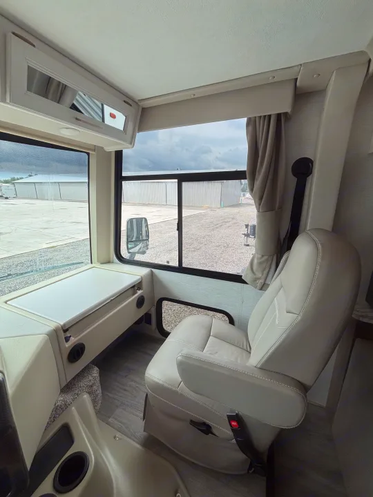 RV rental interior: driver's comfy seat, fold-out table, and large windows offer a great view for travel.. Thor Resonate 2024