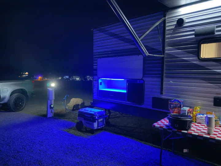 Nighttime rv rental campsite, glowing blue, features a snack table, cooler, and power pedestal.. Jayco Jay-flight 2026