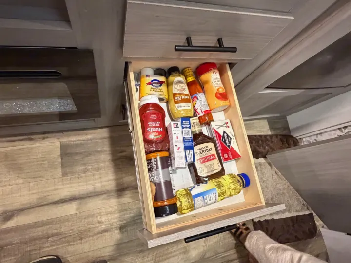 This RV rental kitchen drawer is well-stocked with cooking essentials: condiments, oil, coffee creamer, and matches.. Dutchmen Coleman 2024