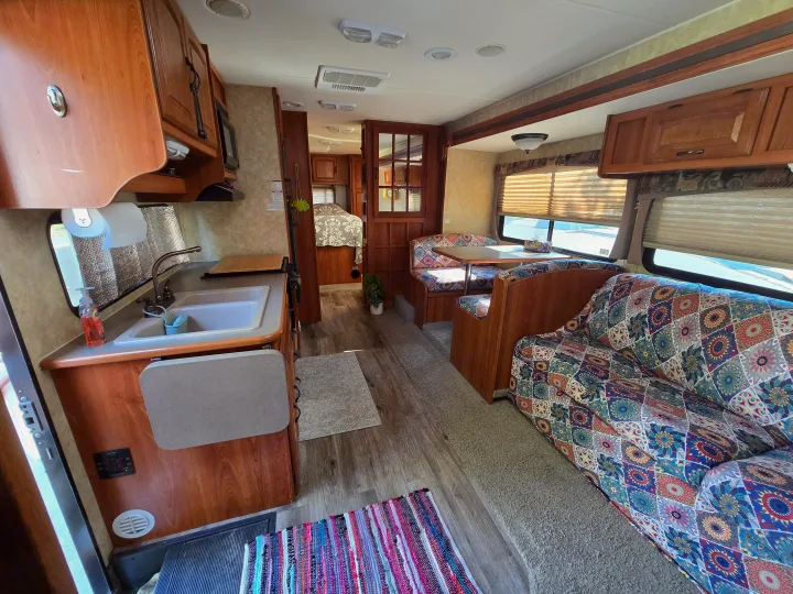 Inside this rv rental: a well-appointed kitchen, dinette, and colorful living space with a sofa. Bedroom seen through door.. Coachmen Freedom Express 2008