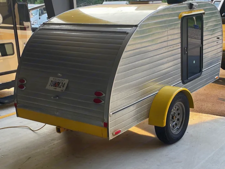 Compact silver teardrop RV rental with yellow trim and fenders, perfect for cozy adventures.. hand built teardrop 2016