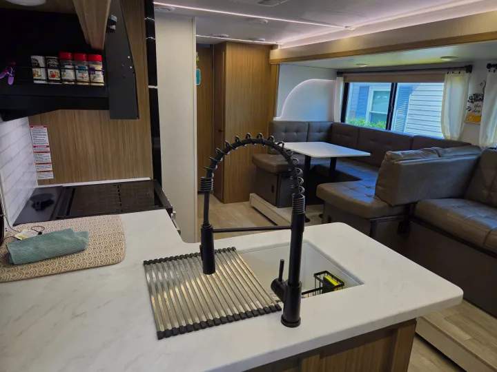 RV rental: Bright interior featuring a sleek kitchen with a black faucet, a practical sink, and a cozy dinette.. Forest River Wildwood X-Lite 2025