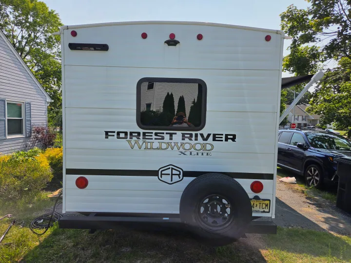 Back of an RV rental: Forest River Wildwood X-Lite with spare tire, NJ plate, and reflection of the photographer in the window.. Forest River Wildwood X-Lite 2025