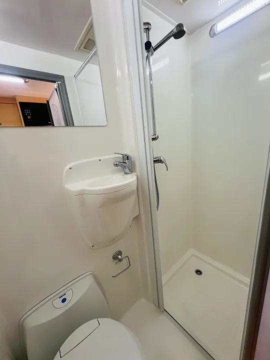 This RV rental features a compact bathroom with a shower, toilet, and wall-mounted sink, optimized for space.. Mercedes-Benz Other 2018