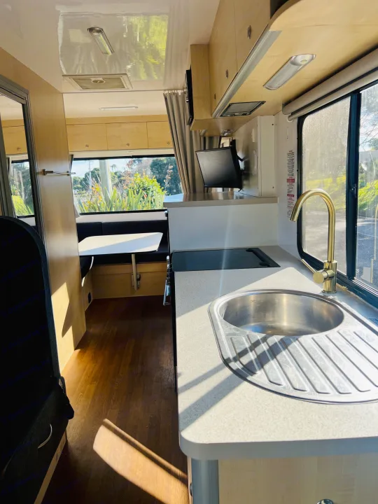 Bright rv rental living space: kitchenette with sink & stovetop, dinette, and light wood interior bathed in natural light.. Mercedes-Benz Other 2018