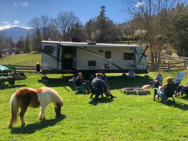 Enjoying an RV rental adventure! Friends and family relax by a fire pit with a pony grazing, surrounded by mountains.. Cruiser RV Shadow Cruiser 2019