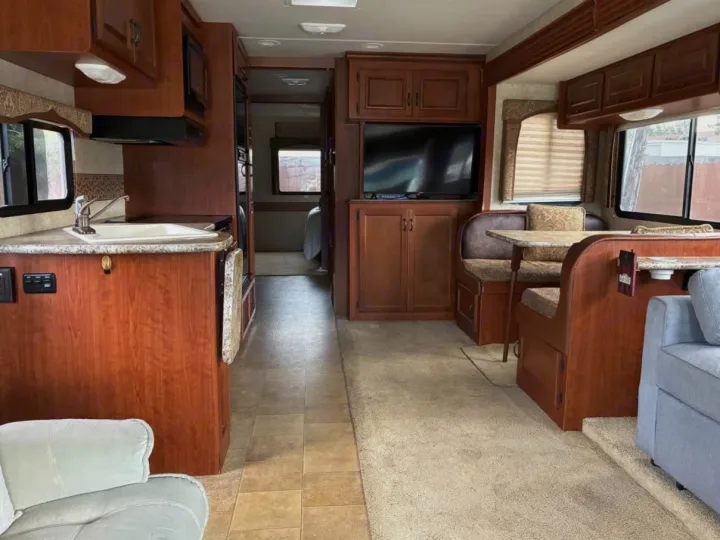 Spacious RV rental interior featuring a well-equipped kitchen, cozy dining booth, and comfortable living area.. Coachmen Thor Motor Coach 2009