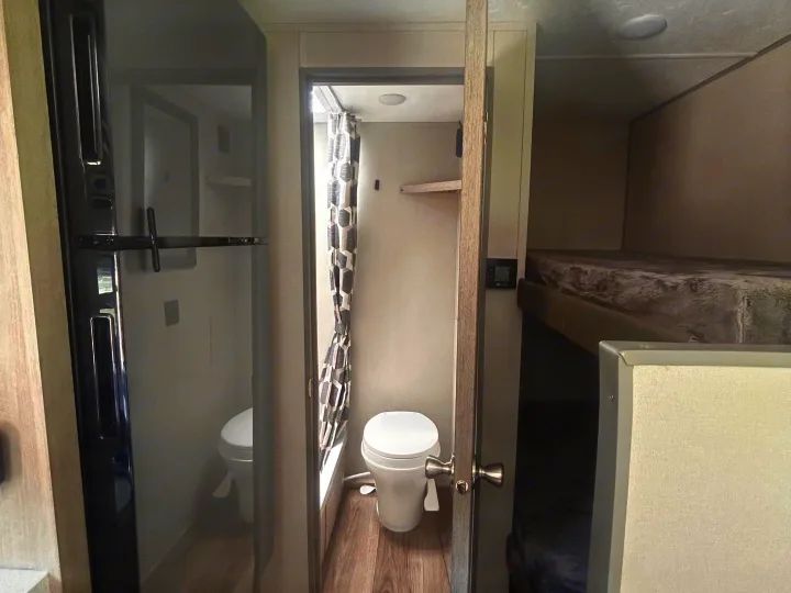 RV rental interior: compact layout featuring refrigerator, small bathroom with toilet, and cozy bunk beds.. Coachmen Catalina Summit Series 7 2026