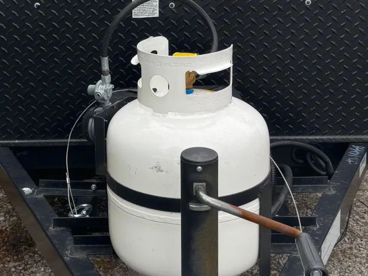 An RV rental's white propane tank & regulator, secured on the trailer frame. Provides essential gas for your trip.. Forest River Coachmen Clipper 2023