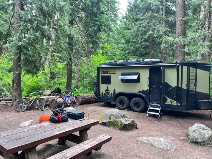 This RV rental, parked in a lush forest campsite with mountain bikes, is perfect for an outdoor adventure getaway.. Imperial Outdoors XploreRV 2022