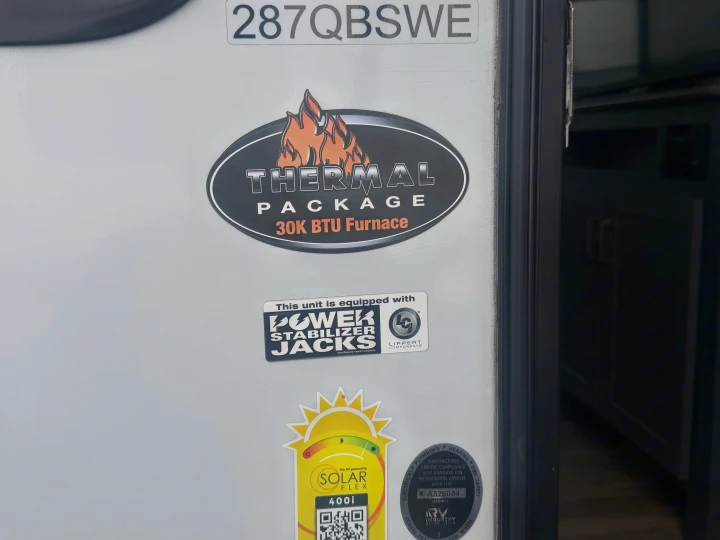 Close-up of an RV rental side with decals: Thermal Package, Solar Flex 400i, Power Stabilizer Jacks, and RVIA certification.. Keystone RV Bullet Ultra Lite 2022