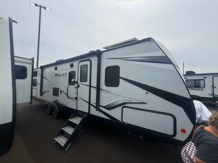 A white "Bullet Ultra Lite" travel trailer, equipped with steps and solar panels, visible for rv rental.. Keystone RV Bullet Ultra Lite 2022