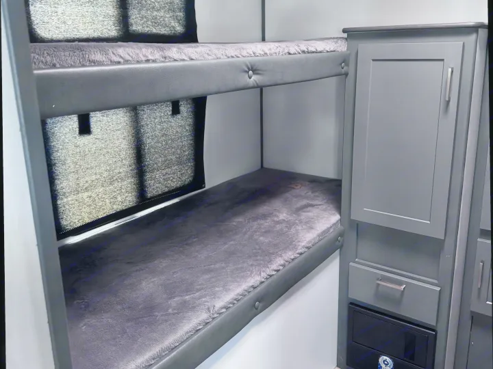 Interior view of an rv rental featuring cozy bunk beds with dark gray mattresses and an adjacent storage cabinet.. Keystone RV Bullet Ultra Lite 2022