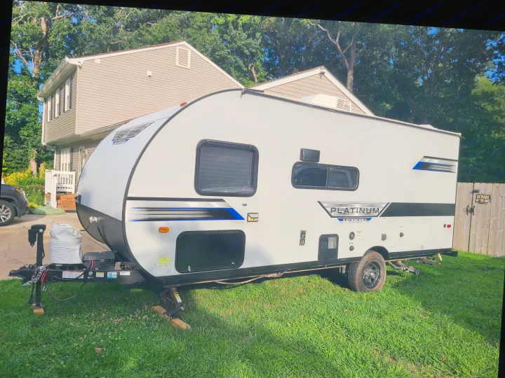 Modern light grey travel trailer, an ideal rv rental, parked in a sunny yard with a house and trees in the background.. Forest River Salem FSX 2019