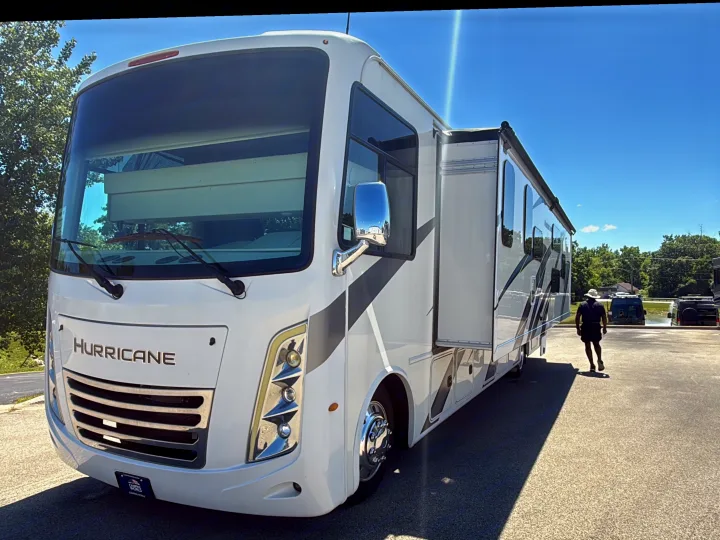 This pristine white Hurricane RV rental, a large motorhome with a deployed slide-out, parked on asphalt on a sunny day.. Thor Hurricane 2022