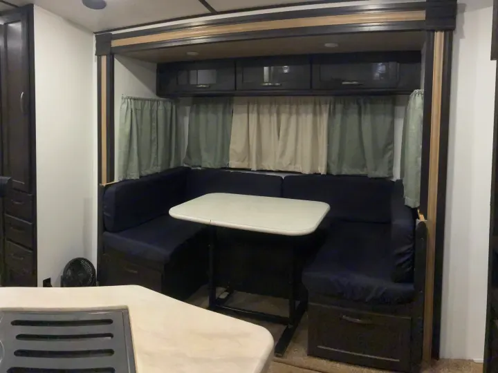 Inside an RV rental: a comfortable U-shaped dinette with a table and convenient overhead cabinets.. Forest River Surveyor Luxury 2019