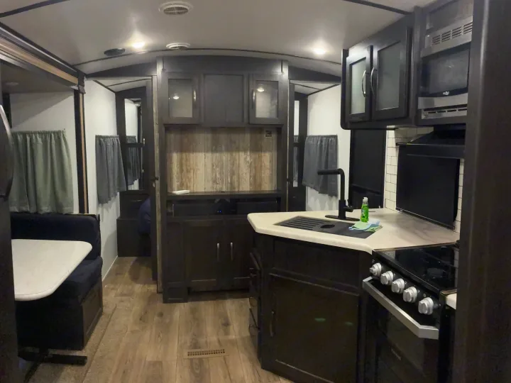 This RV rental features a well-equipped kitchen with a sink, stove, and microwave, plus a comfortable dining booth.. Forest River Surveyor Luxury 2019